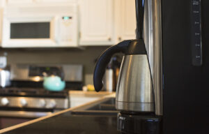 coffee maker in everyday kitchen with microwave and kettle blurred in background